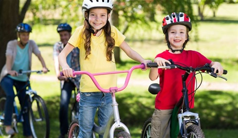 Youth riding bicycles on a river trail.